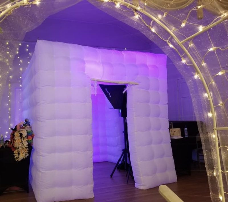 The PhotoBuffs booth lit from within beneath a fairy-light arch
