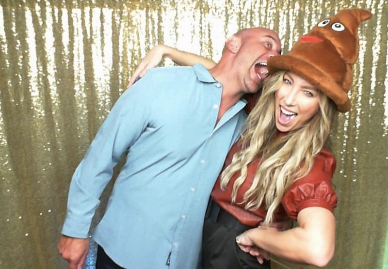 Two guests mid-laugh in a novelty hat against the gold sequin backdrop